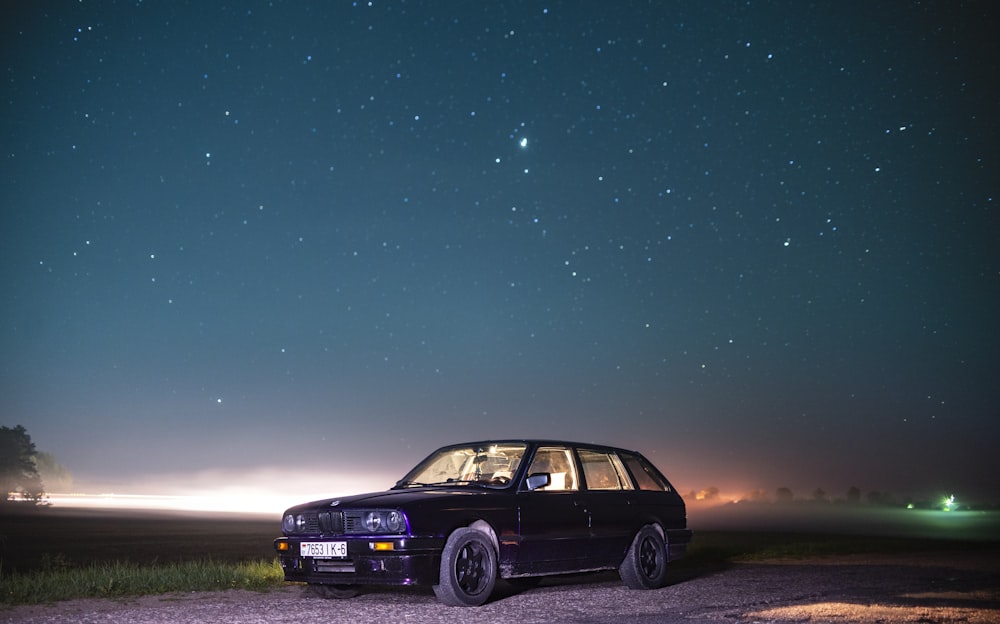 Un'auto parcheggiata su una strada con un cielo stellato sopra