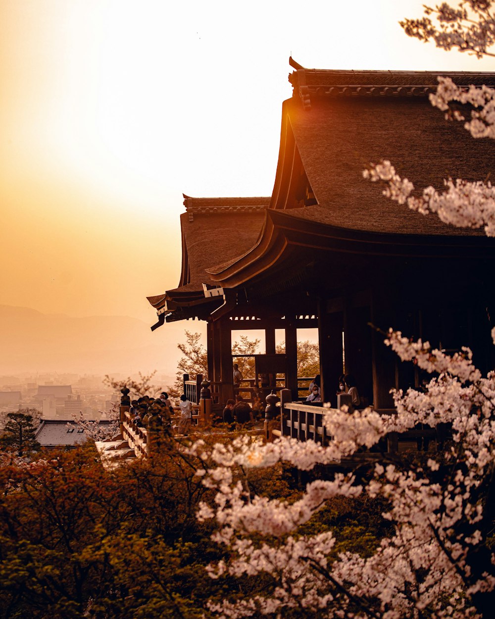 una pagoda con un árbol frente a ella con Kiyomizu-dera al fondo