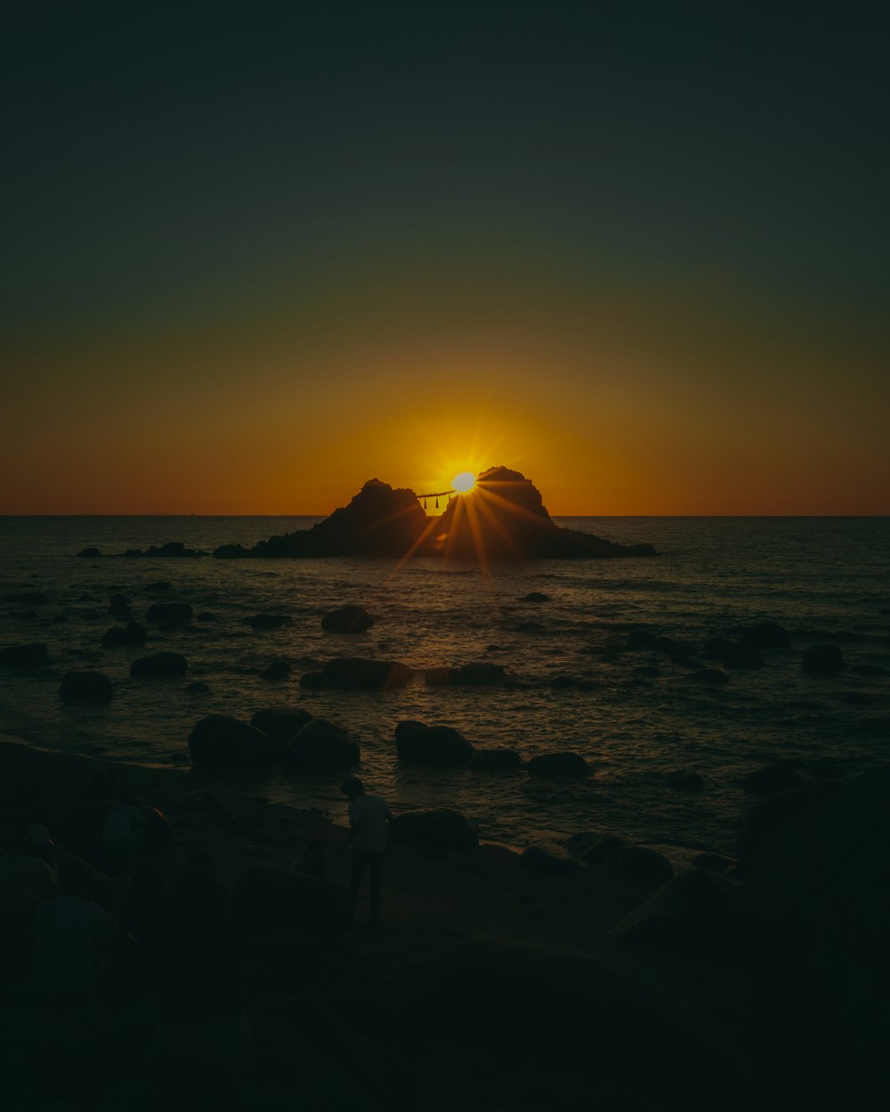 a sunset over a rocky beach