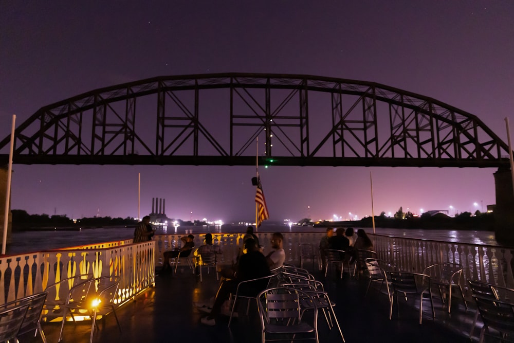 Eine Gruppe von Menschen, die nachts an einem Tisch unter einer Brücke sitzen