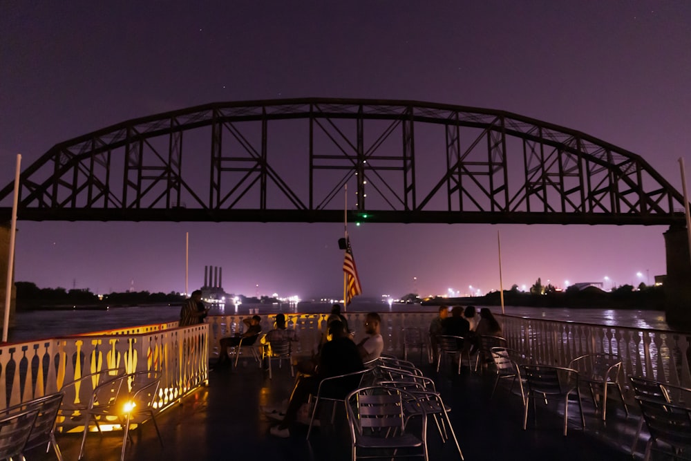 un groupe de personnes assises à une table sous un pont la nuit