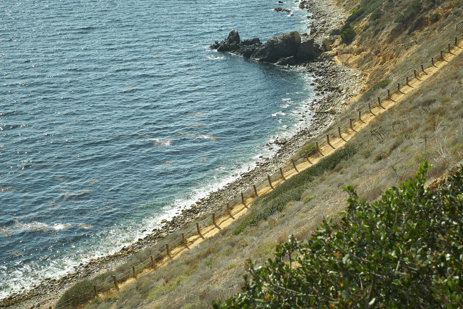 A serene coastal path along the Sicilian shore, with crystal-clear water and vibrant Mediterranean flora.