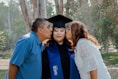 a man kissing a woman in a graduation gown