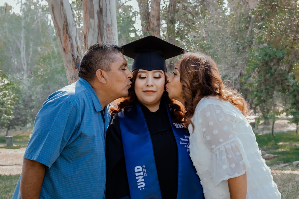 a man kissing a woman in a graduation gown