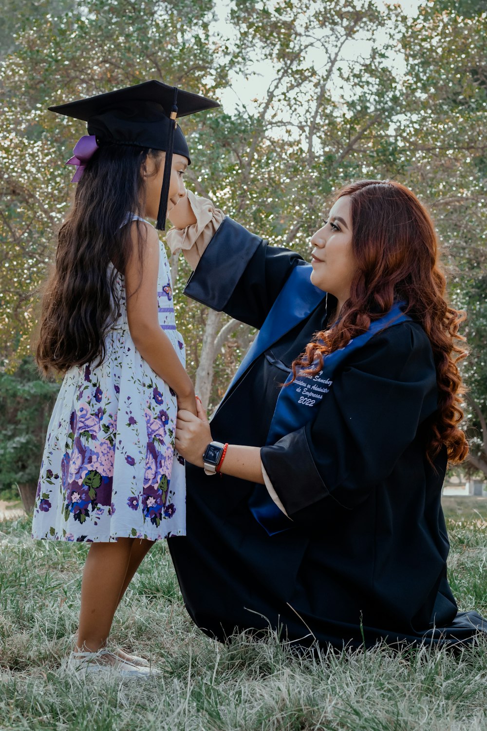a woman in a graduation gown and cap next to a girl in a dress