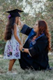 a woman in a graduation gown and cap next to a girl in a dress