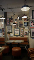 A chic café interior with rustic decor and a series of colorful framed prints along the wall.