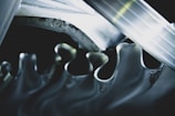 A close-up view of interlocking metallic gears with smooth, wavy edges reflecting light. The gears are intricately aligned, creating a sense of movement and precision.