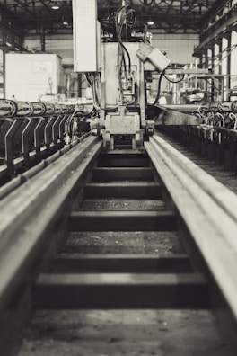 Industrial factory interior with rows of dark machinery in stark black and white contrast.