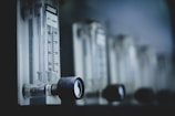 A series of clear glass flow meters with black control knobs on a metallic surface. The measurement scale on one of the devices is clearly visible, with increments marked from 10 to 50. The overall appearance gives a technical and industrial feel, suggesting a laboratory or workshop setting.