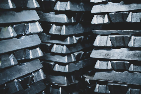 A close-up of shiny metal ingots stacked neatly, reflecting light in a modern warehouse setting.