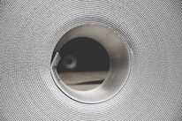 Close-up of hands inspecting a roll of bright-colored coated steel with fine texture.