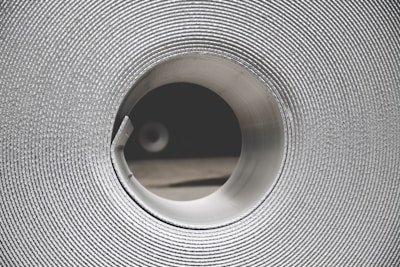 Close-up of hands inspecting a roll of bright-colored coated steel with fine texture.