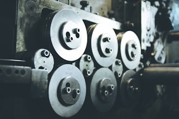 A collection of industrial machine parts featuring multiple large, circular metal components with bolts. The setting appears dimly lit, highlighting the metallic surfaces and their intricacies.