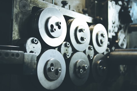 A collection of industrial machine parts featuring multiple large, circular metal components with bolts. The setting appears dimly lit, highlighting the metallic surfaces and their intricacies.