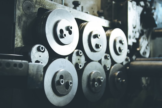 A collection of industrial machine parts featuring multiple large, circular metal components with bolts. The setting appears dimly lit, highlighting the metallic surfaces and their intricacies.