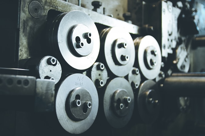 A collection of industrial machine parts featuring multiple large, circular metal components with bolts. The setting appears dimly lit, highlighting the metallic surfaces and their intricacies.