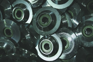 Several metallic gears or bearings with a circular design are stacked together, exhibiting a shiny, reflective surface