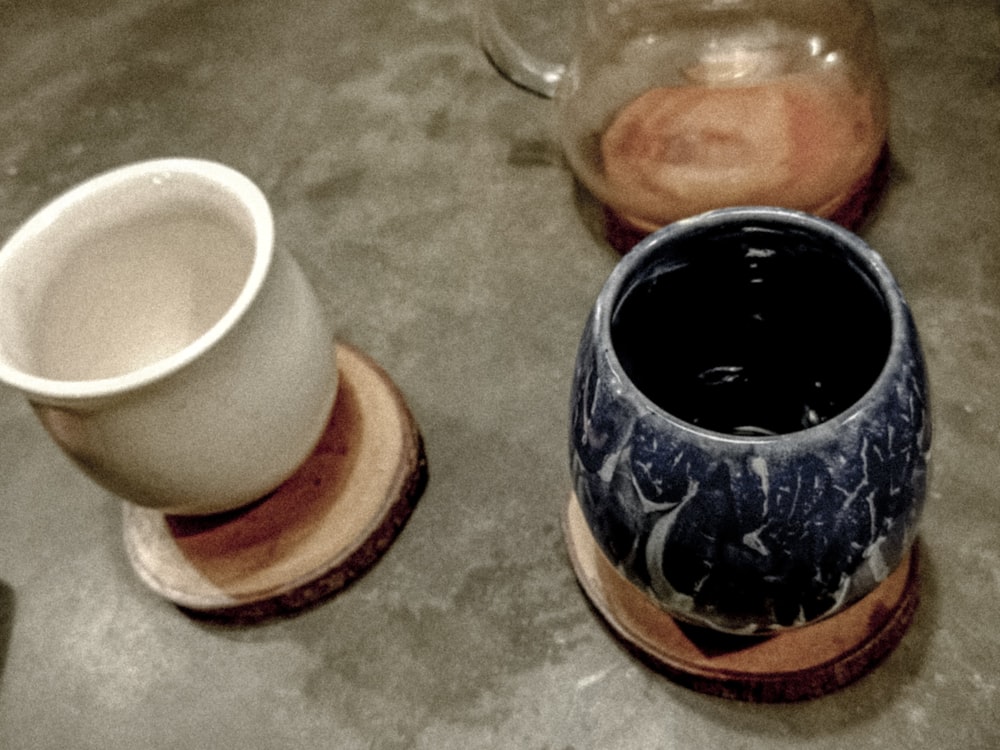 um par de canecas com uma tampa e um copo em uma mesa