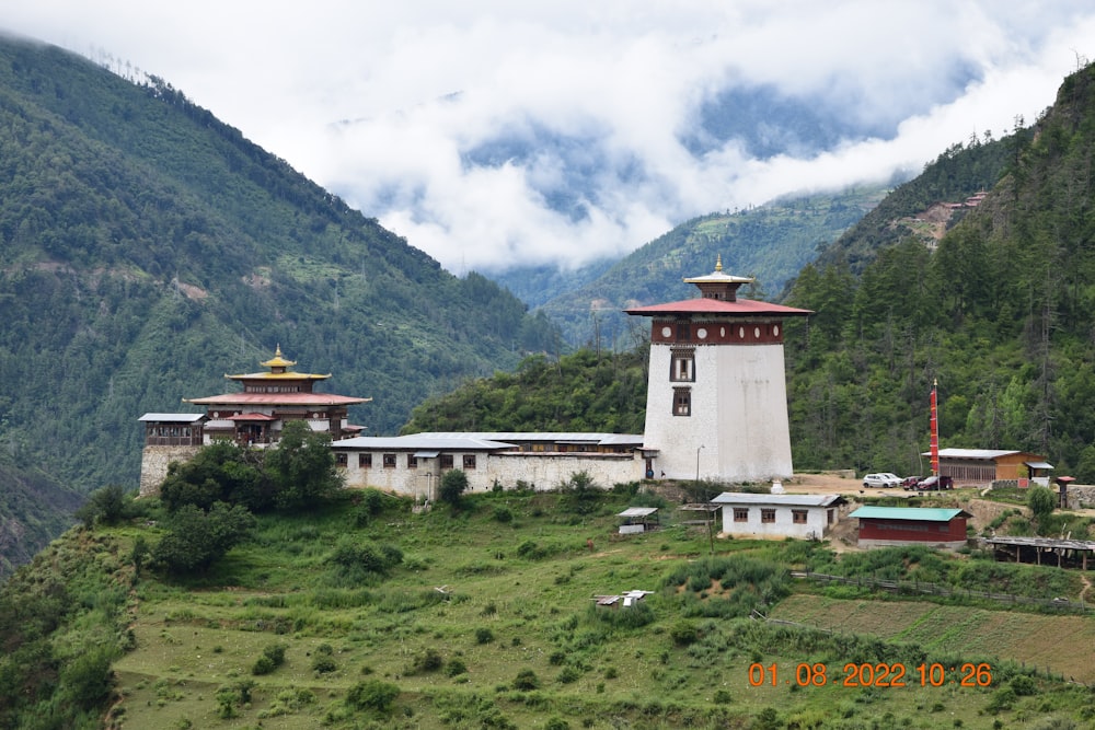 a building in the middle of a grassy area with mountains in the background