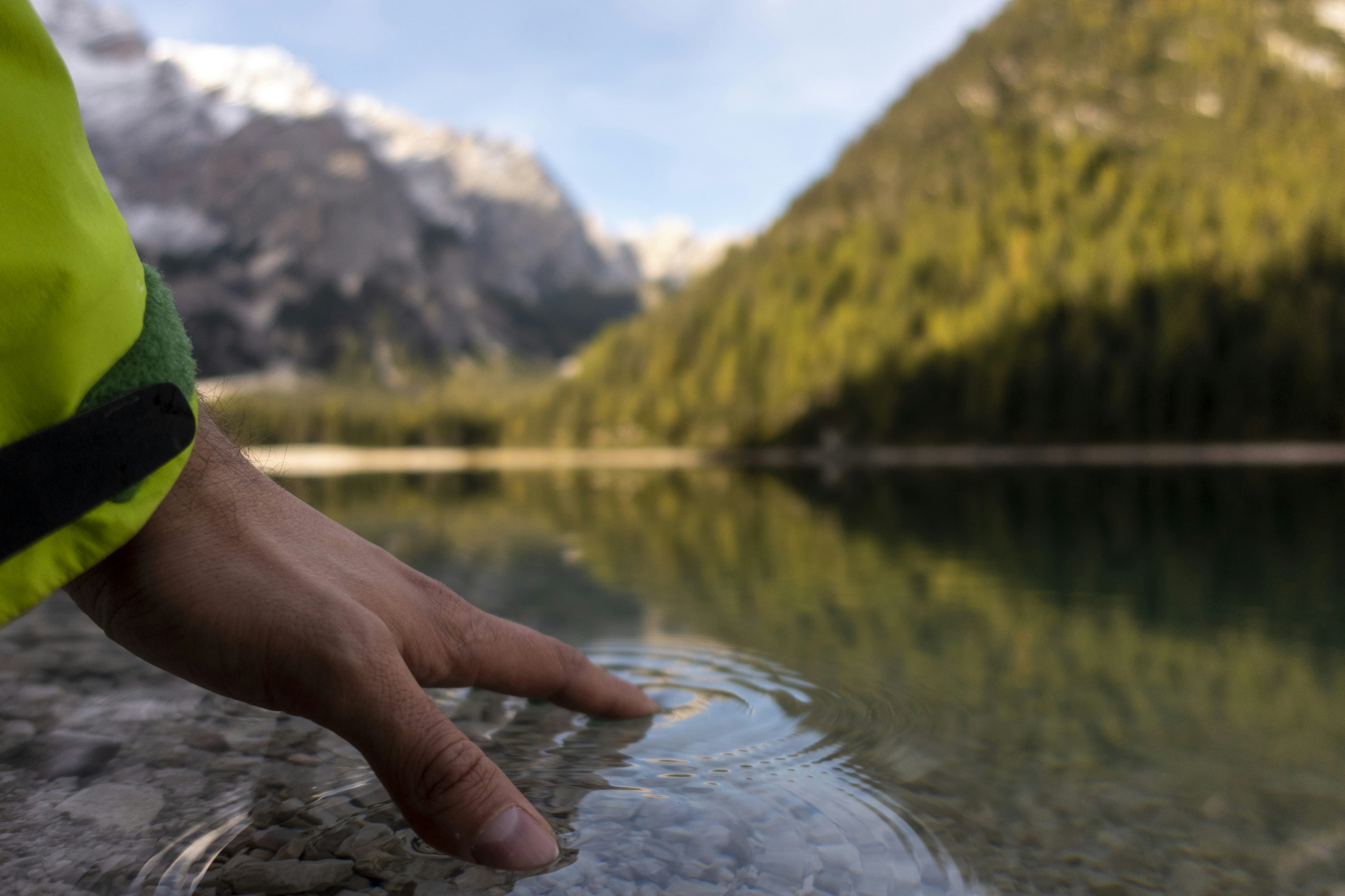 a hand holding a fishing pole over a lake