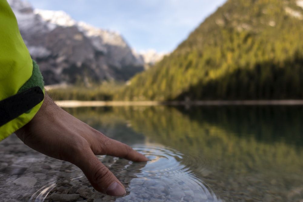a hand holding a fishing pole over a lake