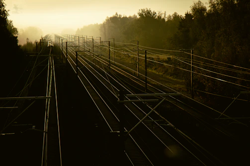 A serene railway track winding through misty mountains at dawn.