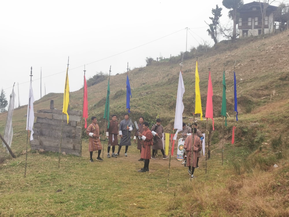 a group of people in clothing standing on a hill with flags