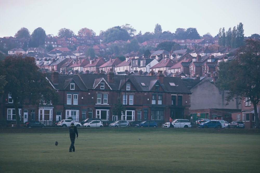 a person walking on a lawn in front of a row of houses
