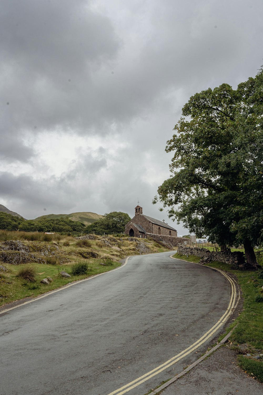 a road with a building on the side and a tree on the side