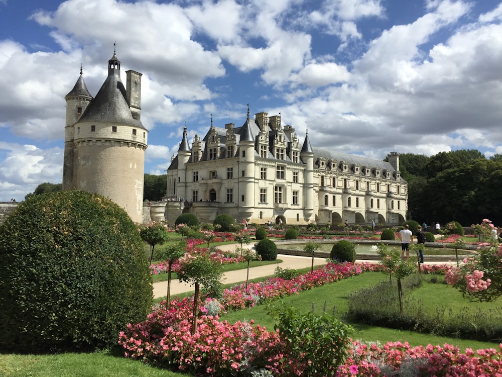 a large white castle with a garden in front of it with Château de Chenonceau in the background