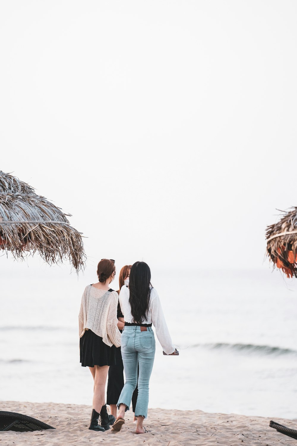 a couple of women standing on a beach looking at the ocean
