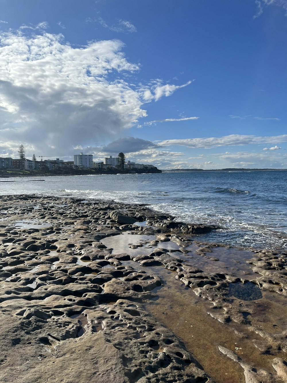 a rocky beach with buildings in the background
