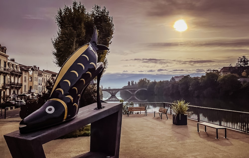 a statue of a frog on a bench in front of a city