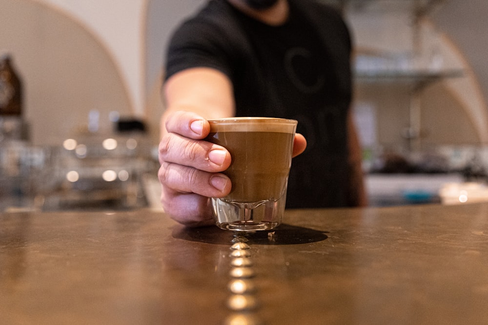 una mano sosteniendo un vaso de líquido