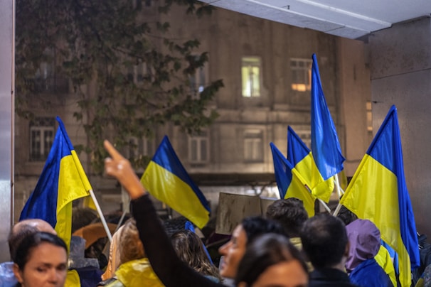 A diverse group of engaged citizens gathered in a community meeting, with navy blue and yellow banners in the background.