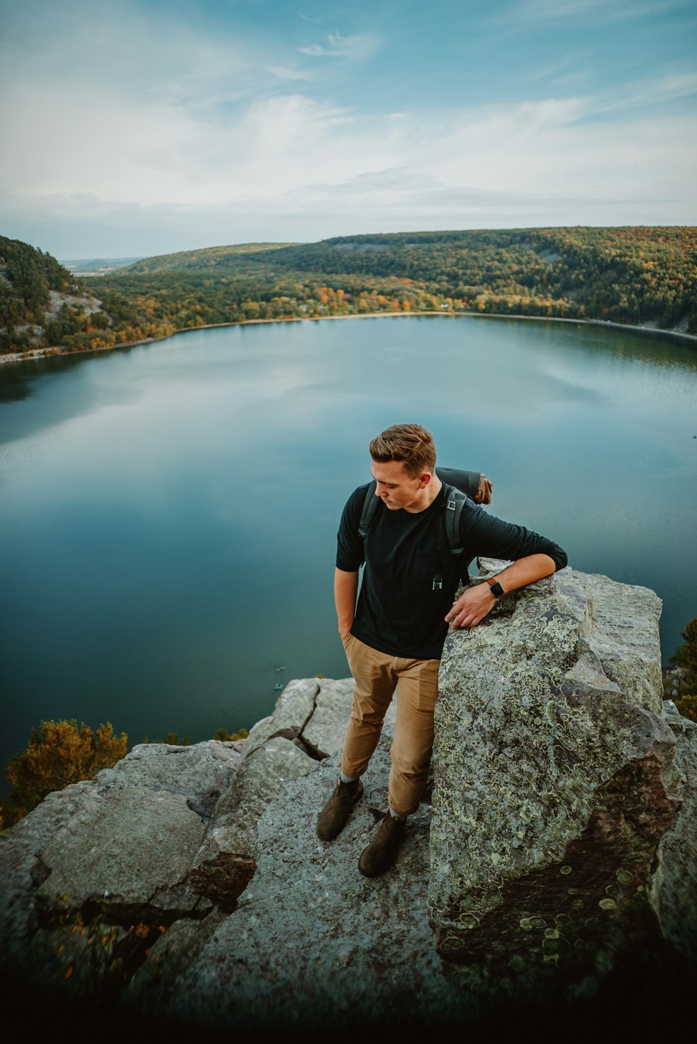 a man standing on a rock by a body of water