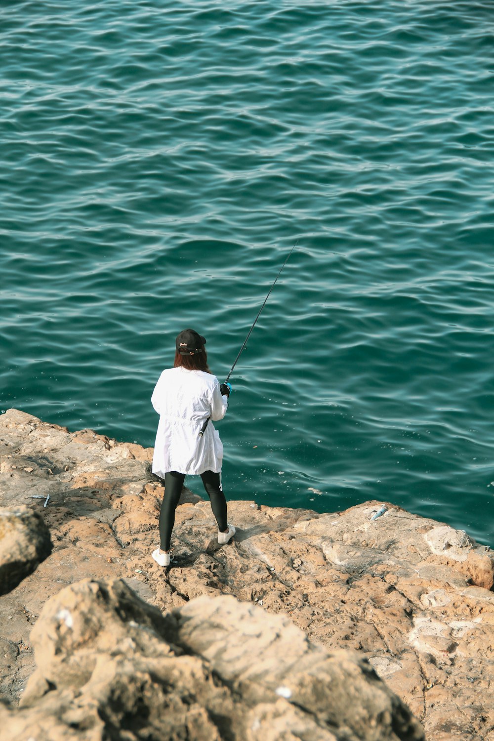 a man fishing on a rocky shore