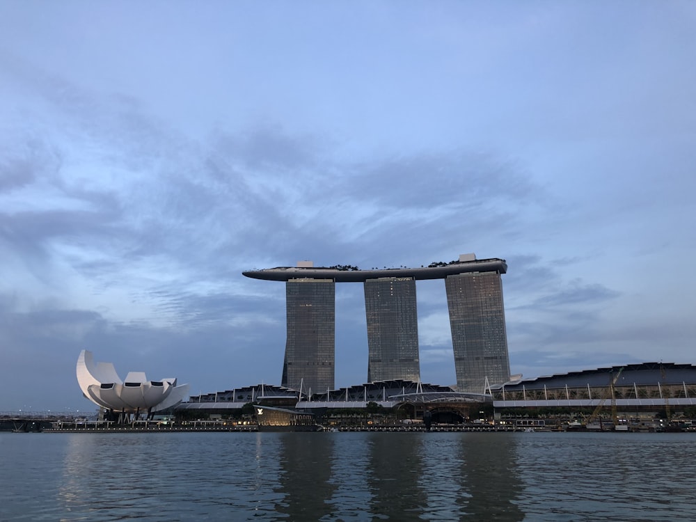 a large building next to a body of water with Marina Bay Sands in the background