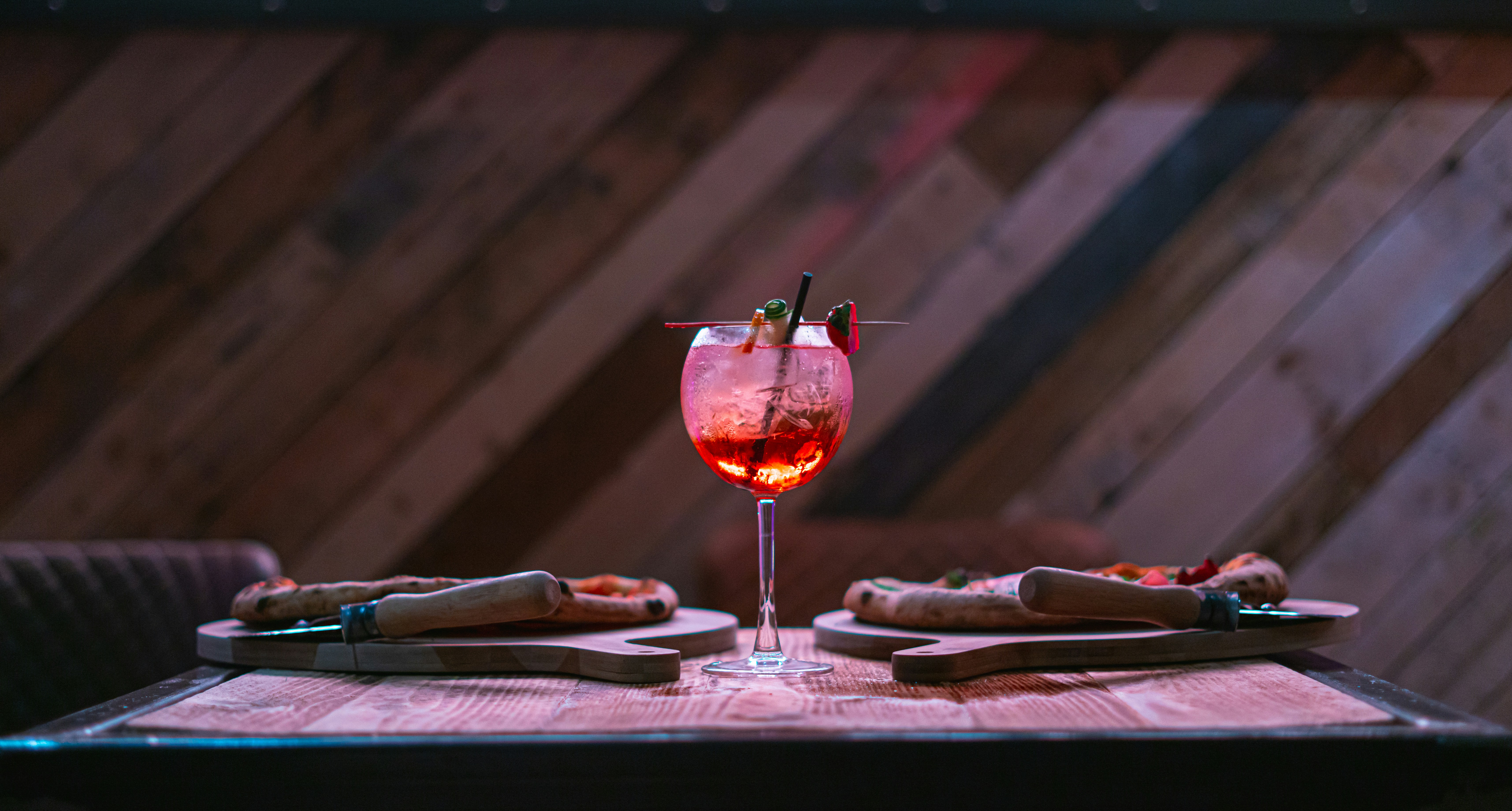 a glass of red wine on a table with a napkin and a knife