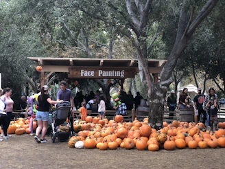 Visitors enjoying a lively craft demonstration at the fall festival under colorful autumn trees.