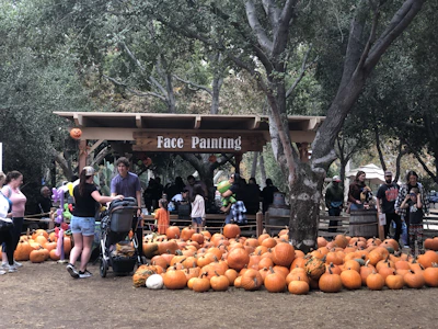 Visitors enjoying a lively craft demonstration at the fall festival under colorful autumn trees.