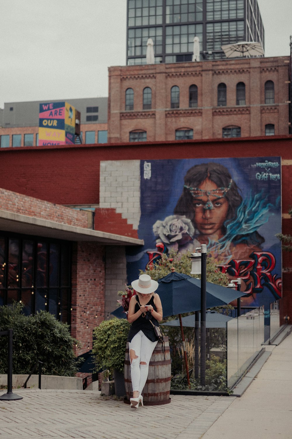 a person standing in front of a building with a mural on it