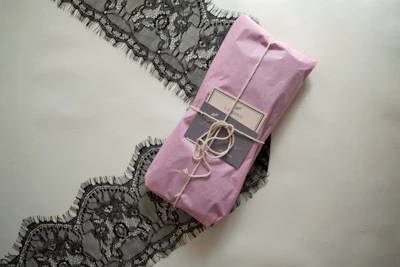 A soft pastel pink package wrapped with a delicate coral ribbon, ready to be returned.