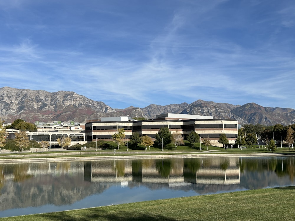 a building with a pond in front of it and mountains in the background