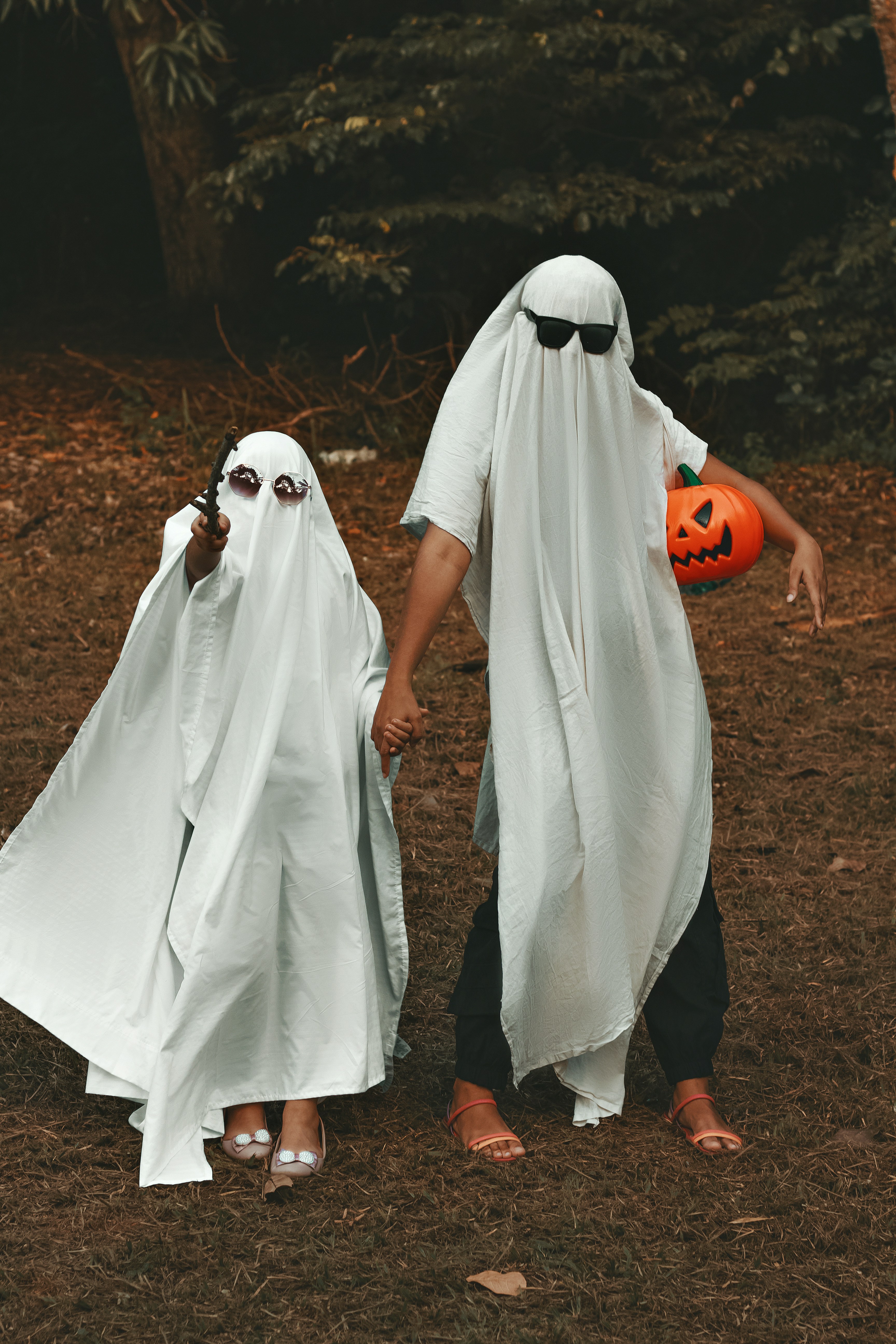 two people wearing white robes and holding pumpkins