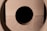 Circular cutouts in light wood create a symmetrical pattern with a dark void in the center.