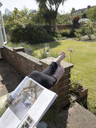 a person lying on a brick wall with a book and a glass of wine