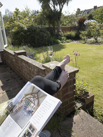 a person lying on a brick wall with a book and a glass of wine
