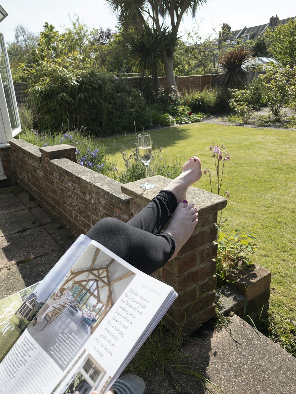 a person lying on a brick wall with a book and a glass of wine